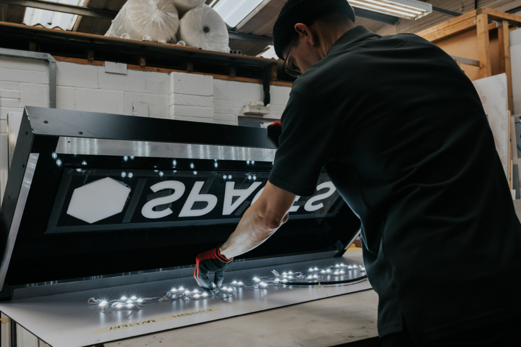 A team member from Elmtree Signs works on a light box