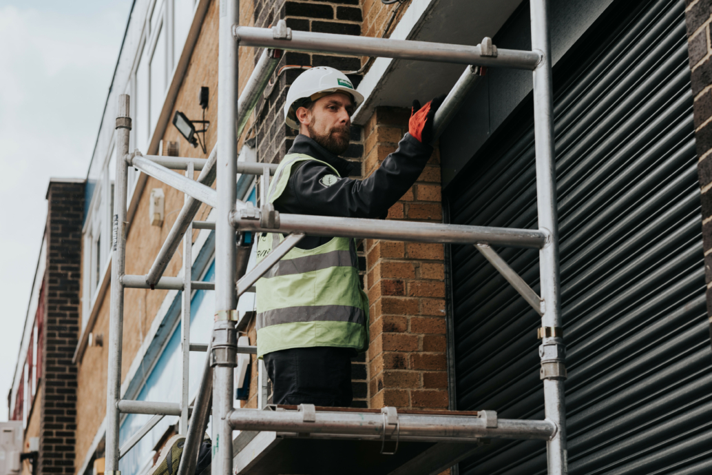 An Elmtree Signs team member stands on scaffolding