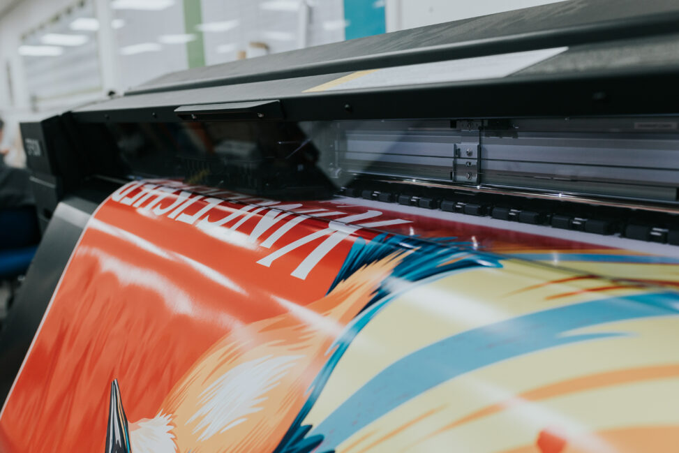 A sign for Kingfisher Beer being printed from a large machine